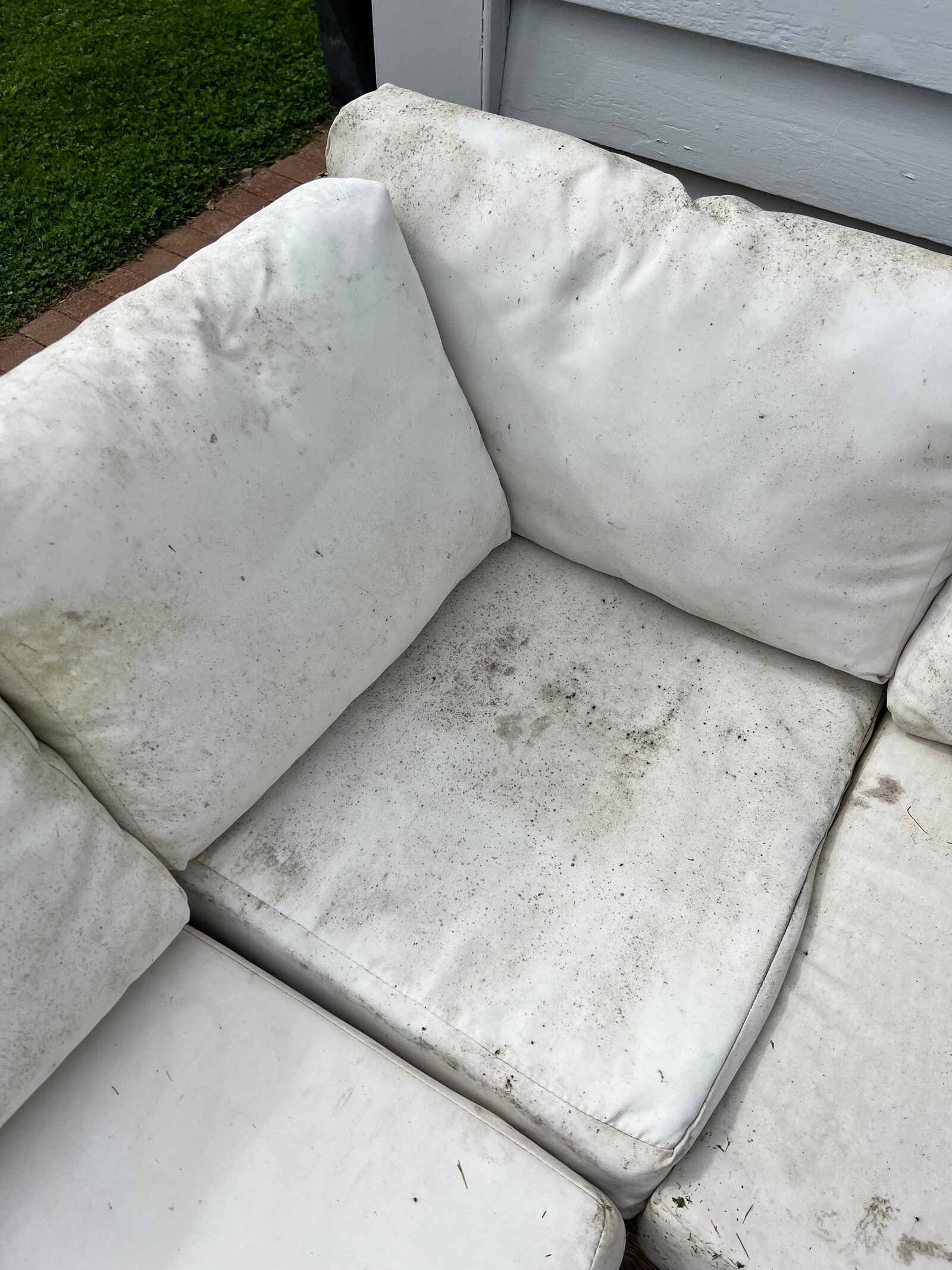 Close-up of mould and water stains across a white outdoor cushion
